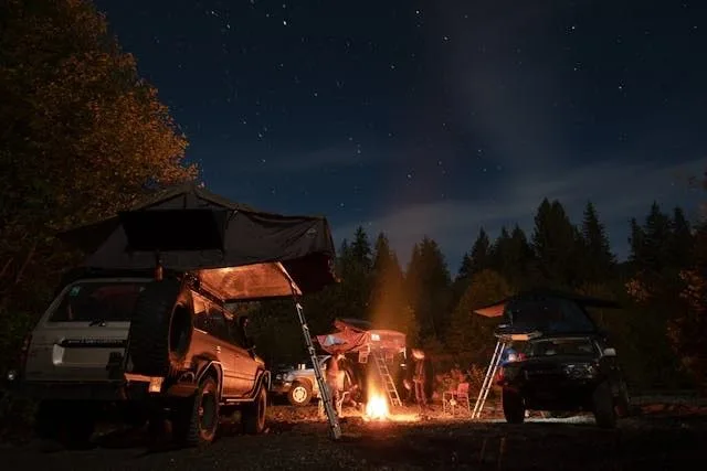 Night camping scene with SUV car tent and bonfire under starry sky
