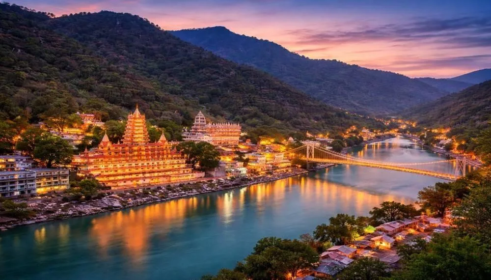 Best honeymoon Destination Evening view of Rishikesh with illuminated temples along the Ganga river and Ram Jhula bridge in the background”