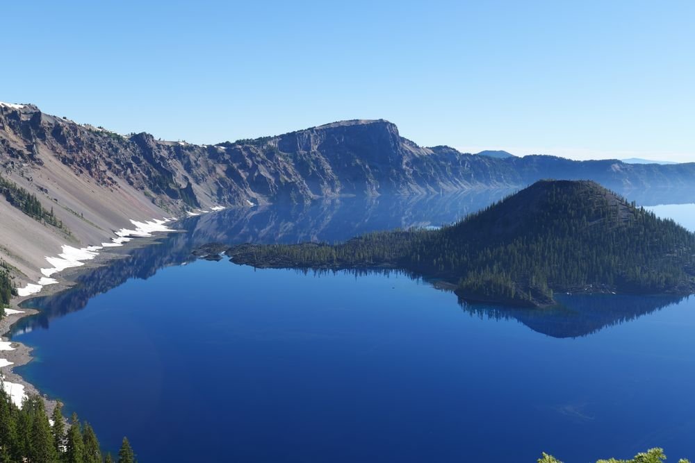 The deep cobalt blue waters of Crater Lake surrounding Wizard Island, showcasing one of the best national parks to visit in September.