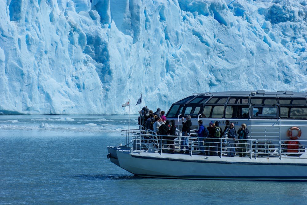 A tourist boat near a massive blue glacier wall in Glacier Bay, one of the best national parks to visit in June.